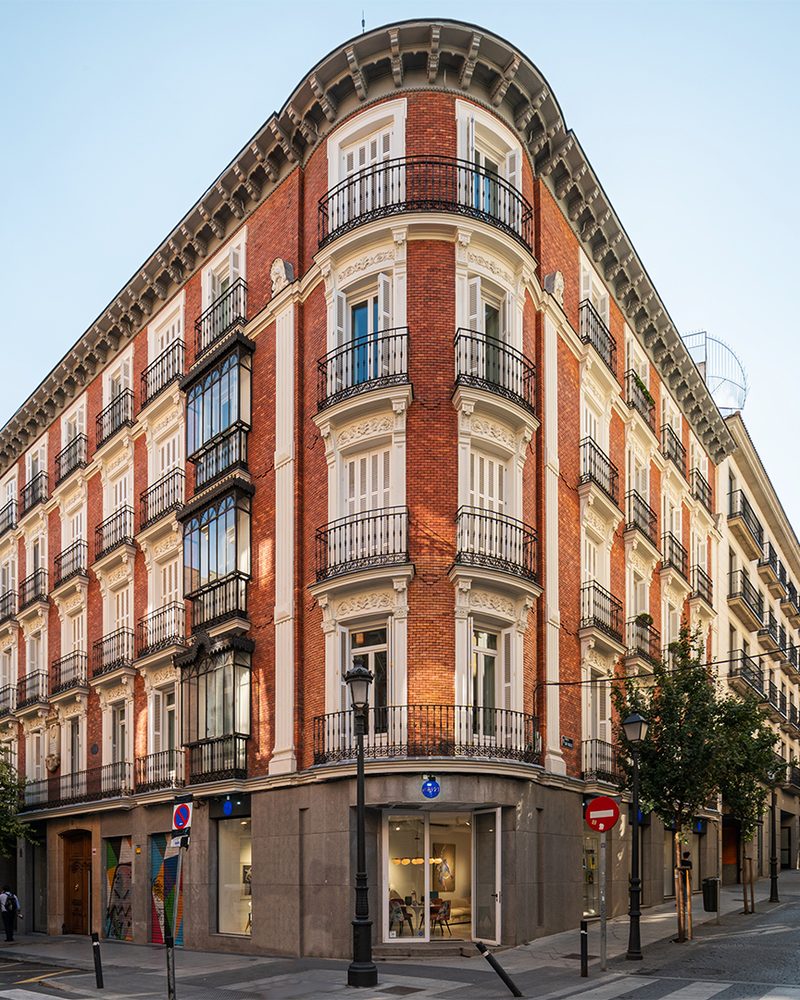 Edificio de ladrillo rojo en esquina en la calle Barquillo, en Madrid, con balconeras de madera